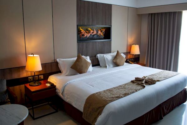 A cozy hotel room with a large bed, two bedside lamps, and a decorative art piece above the bed, creating a warm and inviting atmosphere.