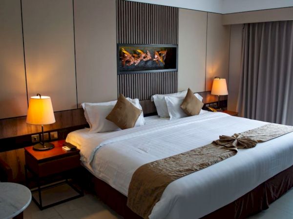 A cozy hotel room with a large bed, two bedside lamps, and a decorative art piece above the bed, creating a warm and inviting atmosphere.