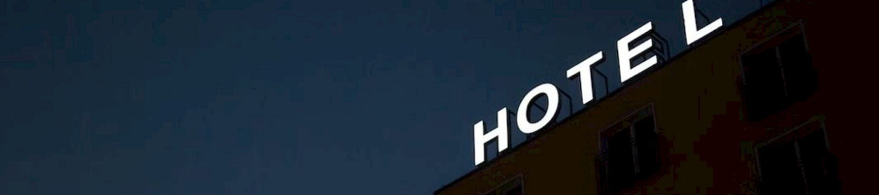 A building with a neon sign reads "HOTEL" against a dark sky, with one letter unlit.