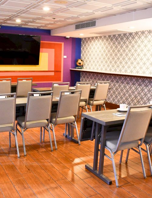 A brightly colored conference room with chairs, a large screen, and a patterned wall, arranged for a meeting or presentation.