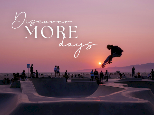 A sunset skatepark with people watching as a skateboarder jumps mid-air, with text reading &ldquo;Discover more days.&rdquo;