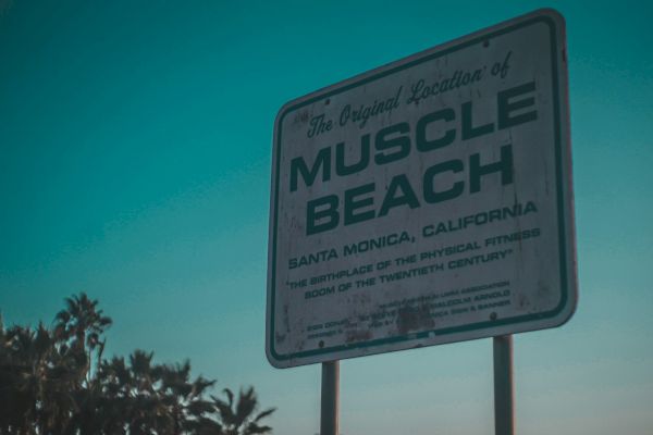 A sign for "Muscle Beach" in Santa Monica, California, highlighting its historical significance in fitness culture.